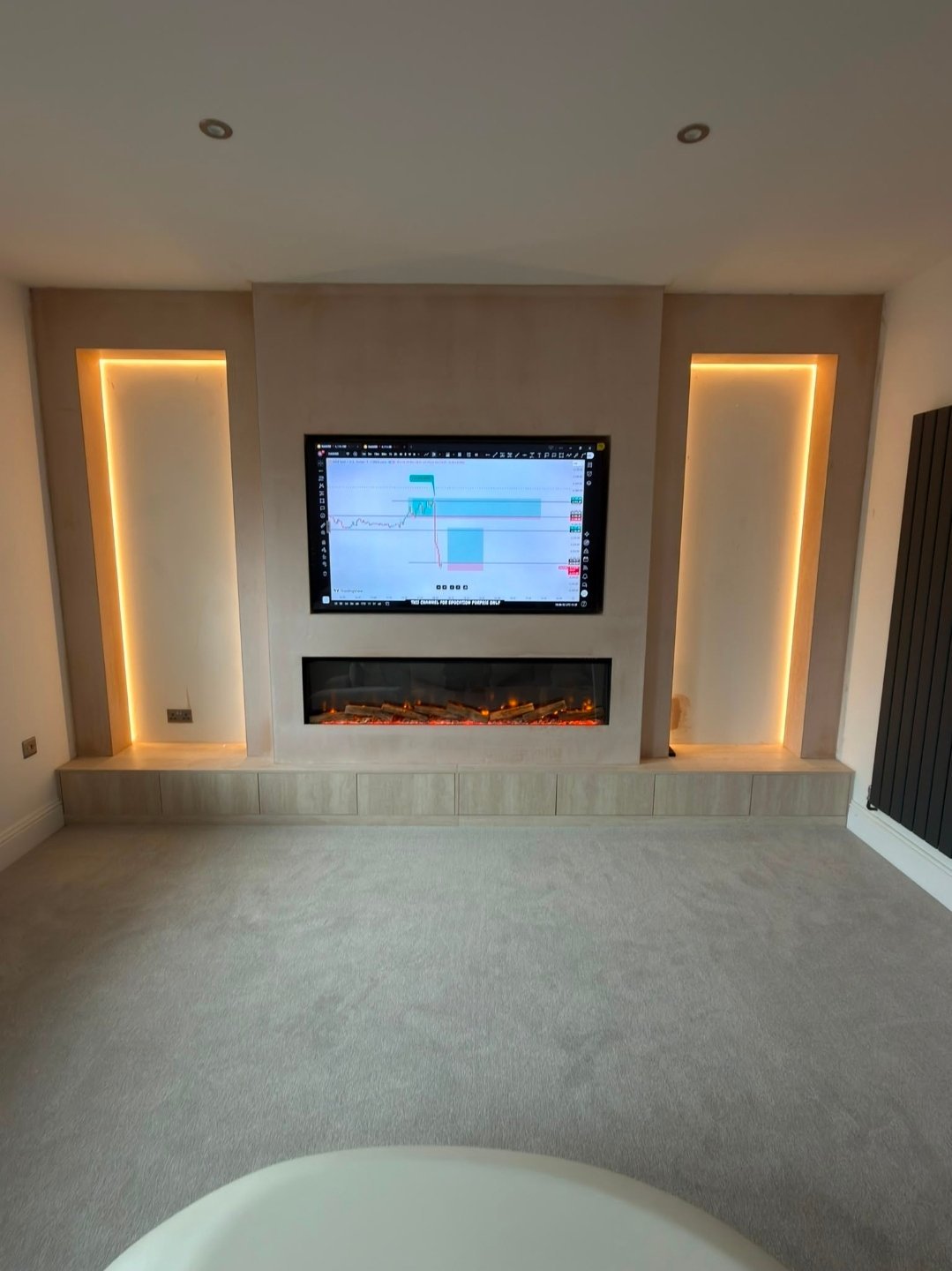 Modern living room with mounted TV, electric fireplace, and two illuminated wall panels with warm ambient lighting