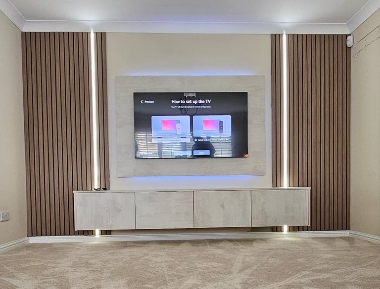 Modern living room with wall-mounted TV on white accent wall, low media console, taupe curtains, and ambient lighting