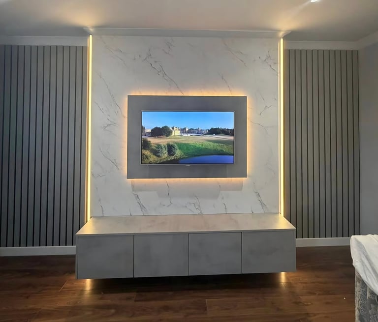 Modern living room with wall-mounted TV showing a golf course landscape, surrounded by marble accent wall and warm LED lighting